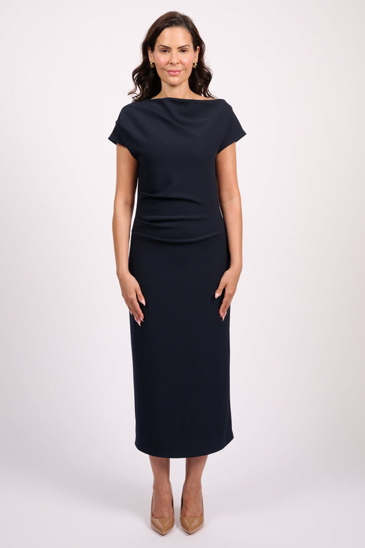 A woman modeling a dark navy midi dress with short cap sleeves, a boat neckline, and a fitted silhouette, standing against a light gray studio background.