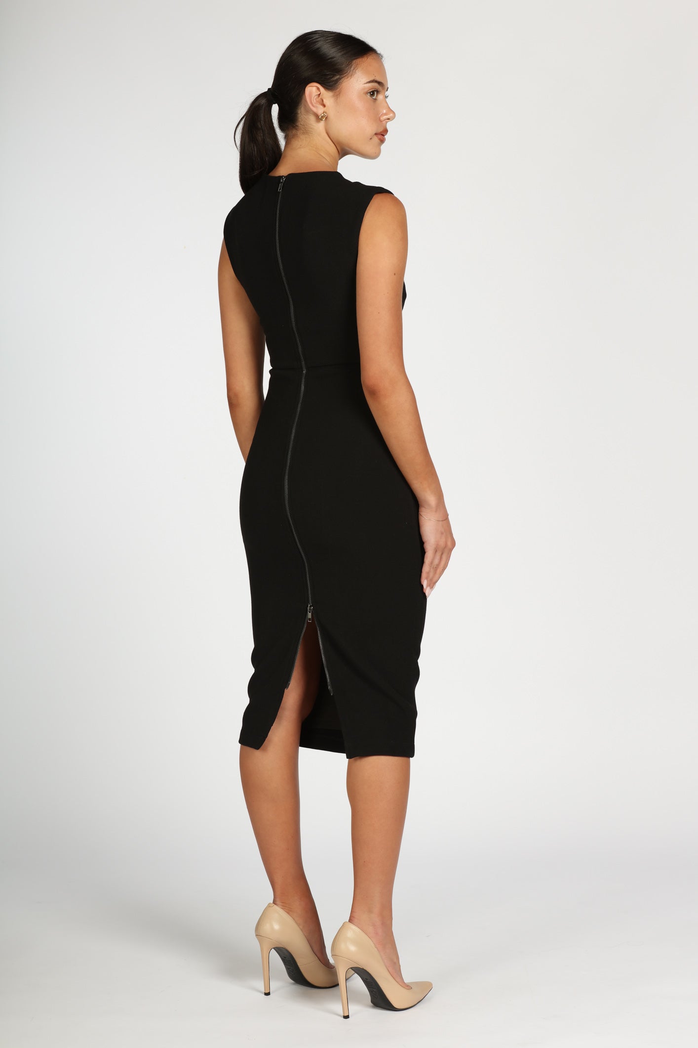 Woman wearing a black dress with a slit on a white background